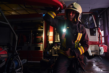 Fototapeta na wymiar Fireman wearing a protective uniform with flashlight included working in a fire station garage