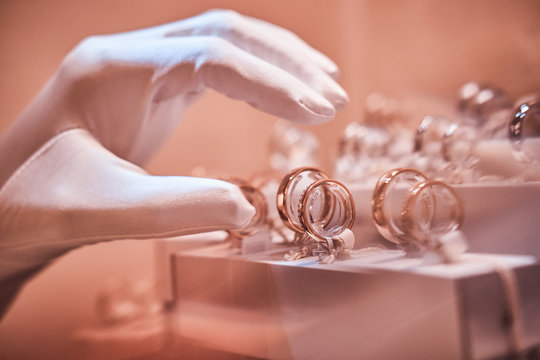 Hand in gloves takes to exclusive rings on the showcase of a luxury jewelry store