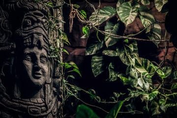 Beautiful rocky monument with a carved image of a human face in the jungle. Close-up view