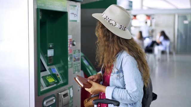 Unrecognizable female charging travel pass while standing near modern machine on railway station