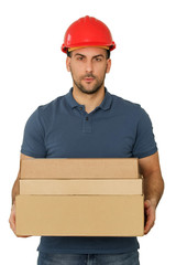Young handsome worker in red helmet holding cardboard boxes, studio shot isolated on white