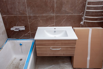 Unfinished Interior of repair and renovation bathroom.  A bathroom remodeling project and design wetroom. Brown marble on the walls. Furniture in protective film.