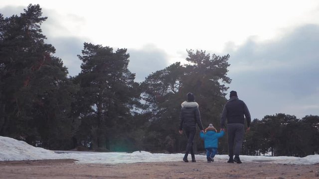 Happy family walks in winter forest. Parenthood, season and people concept.