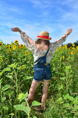 Rücken eines Mädchen  in kurzer Jeans, Arme fröhlich nach oben, steht im Sonnenblumen Feld
