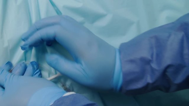 Gloved medical specialist twists a syringe tube into IV or catheter in hospital
