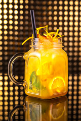 Yellow fruit cocktail lemonade with fresh lemon in vintage jar