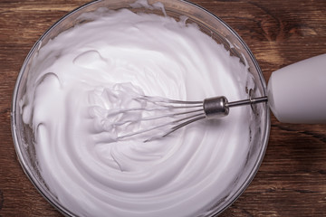 Whipped egg whites for cream on wooden table, top view