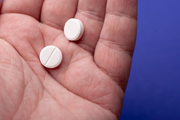 Close-up shot of a hand holding two pills