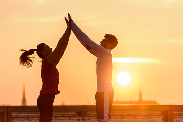 Young sport couple standing together on the bridge after training giving high five. Challenge and...