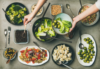 Vegan dinner table setting. Healthy dishes in plates on table. Flat-lay of vegetable salads,...