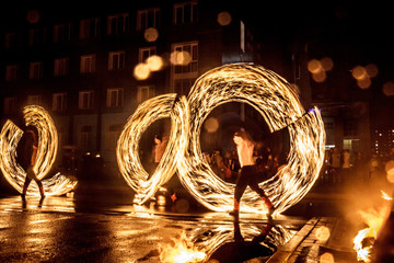 Night performance fire show in front of a crowd of people on the street in night, soft focus background.