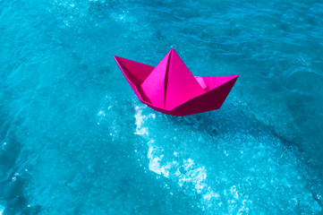 A boat made of colored paper in the snow. Origami handicraft.