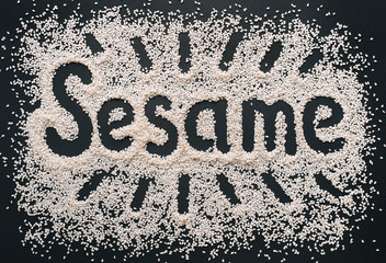 The funny word Sesame is written among a multitude of grains on a black background. Symbol of healthy nutrition and vegetarianism.