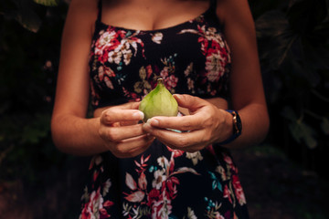 young woman with floral dress and a fig in her hands