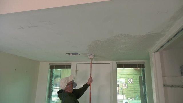 A workman texturing a ceiling with stucco plaster