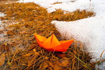 A boat made of colored paper in the snow. Origami handicraft.