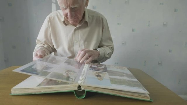 Senior caucasian man looking through an old photo album themes of memories nostalgia photos retired