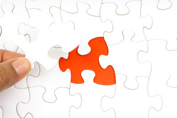 Fototapeta premium Hand put the last piece of jigsaw puzzle closeup to complete the mission. Selective focus and crop fragment