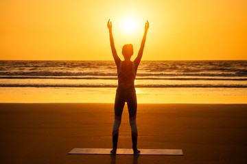 Fototapeta premium copyspace woman doing yoga performing asanas and enjoying life at sunset on the beach sea copy space