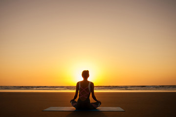 copyspace woman doing yoga performing asanas and enjoying life at sunset on the beach sea copy space
