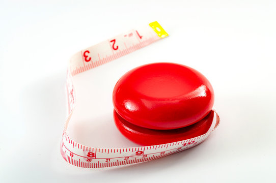 Yo-yo dieting, yo yo effect or weight cycling concept theme with a yoyo toy wrapped in tape measure or measuring tape symbolizing the fluctuating of a unsuccessful diet, isolated on white background