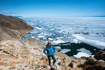 View above big beautiful lake Baikal with Ice floes floating on the water with girl wears blue jacket, Russia