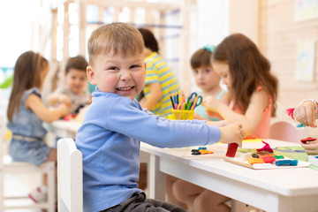 smiling kid playing with colorful clay with kindergarten group