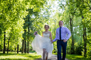 Russian bride and groom together in green city park