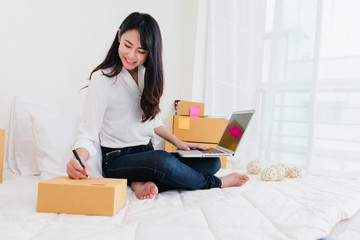 Fototapeta na wymiar Freelancer woman working sme business at office in home interior smile checking order from laptop for customer and online delivery for ready packing in bedroom.