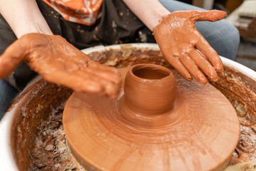 Craftsman hands making pottery bowl. Woman working on potter wheel . Family business shop sculpts pot from clay view top.