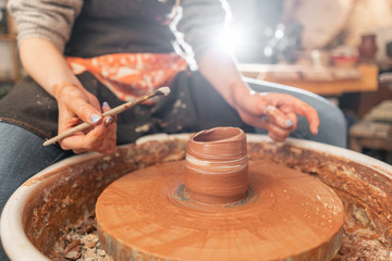 Craftsman hands making pottery bowl. Woman working on potter wheel . Family business shop sculpts pot from clay view top.