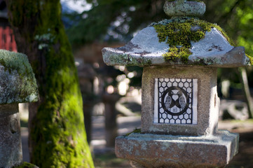 Stone lantern with the logo of two birds in love at the Tamukeyama Hachimangu temple in Nara, Japan