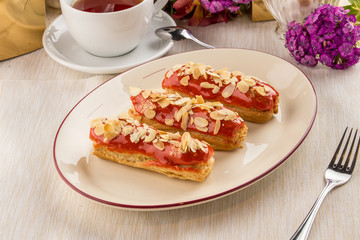 caramel almond eclairs with tea cup on textile napkin
