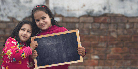 Two happy children holding a blank chalkboard. Education Inspiration Concept.