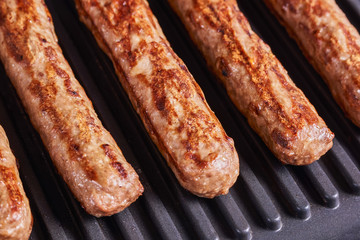 Serbian cevapi, cevapcici, Balkan minced meat kebab. Sausages cooking to grill. Medium degree of roasting. Close-up