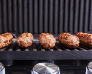 Serbian cevapi, cevapcici, Balkan minced meat kebab. Sausages cooking to grill. Close-up