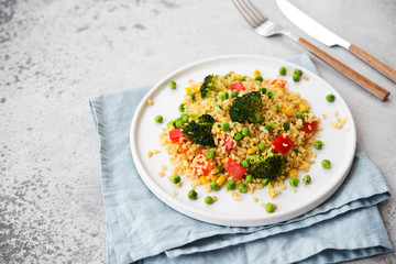 Lenten dish. Bulgur with vegetables in a plate. Pilaf from bulgur, broccoli, green peas, bell peppers and corn.