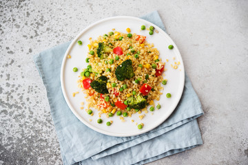 Lenten dish. Bulgur with vegetables in a plate. Pilaf from bulgur, broccoli, green peas, bell peppers and corn.