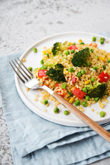 Lenten dish. Bulgur with vegetables in a plate. Pilaf from bulgur, broccoli, green peas, bell peppers and corn.