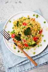 Lenten dish. Bulgur with vegetables in a plate. Pilaf from bulgur, broccoli, green peas, bell peppers and corn.