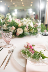 Closeup Table setting with plates and tableware, adorned with flowers. Floral decoration for wedding ceremony romance dining. Wedding banquet , festive decor. Concept of service and catering.
