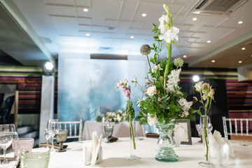 Floral decoration for wedding ceremony romance dining. Wedding banquet , festive decor. Bouquet from spring and summer flowers. Table layout. Restaurant interior. Concept of service and catering.