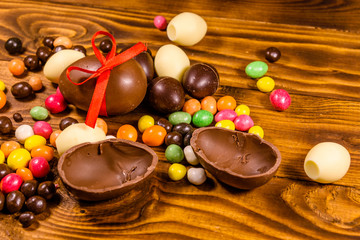 Chocolate easter eggs and multicolored candies on wooden table