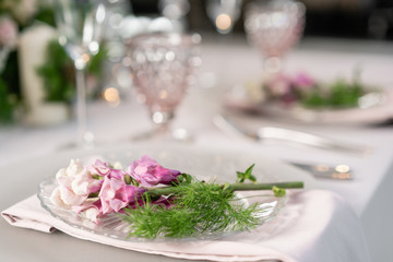 Closeup Table setting with plates and tableware, adorned with flowers. Floral decoration for wedding ceremony romance dining. Wedding banquet , festive decor. Concept of service and catering.