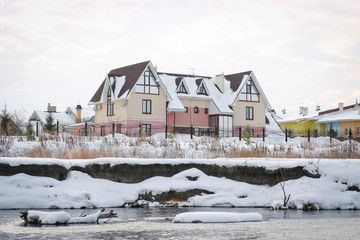 Fototapeta na wymiar Beautiful two-story cottage by the river in winter