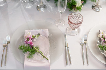 Closeup Table setting with plates and tableware, adorned with flowers. Floral decoration for wedding ceremony romance dining. Wedding banquet , festive decor. Concept of service and catering.
