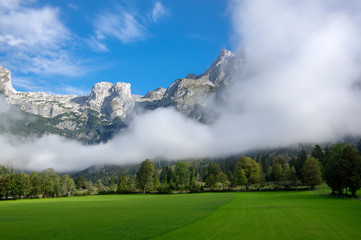 Austrian Verfenveg village Alps mountains autumnal scenery with fog, green meadows and rocks