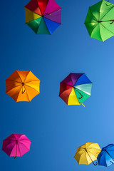 Group of flying umbrellas isolated on blue background, ready for the rain, wallpaper background, bright various colors