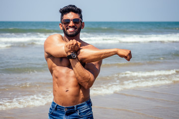 portrait of happy young african man on the beach.Handsome and confident Masculine hard fitness model male body bodybuilder with six pack.India trainer with perfect abs, shoulders,biceps, triceps,chest