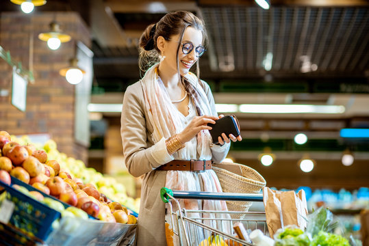 Young woman getting wallet with money while buying food in the supermarket